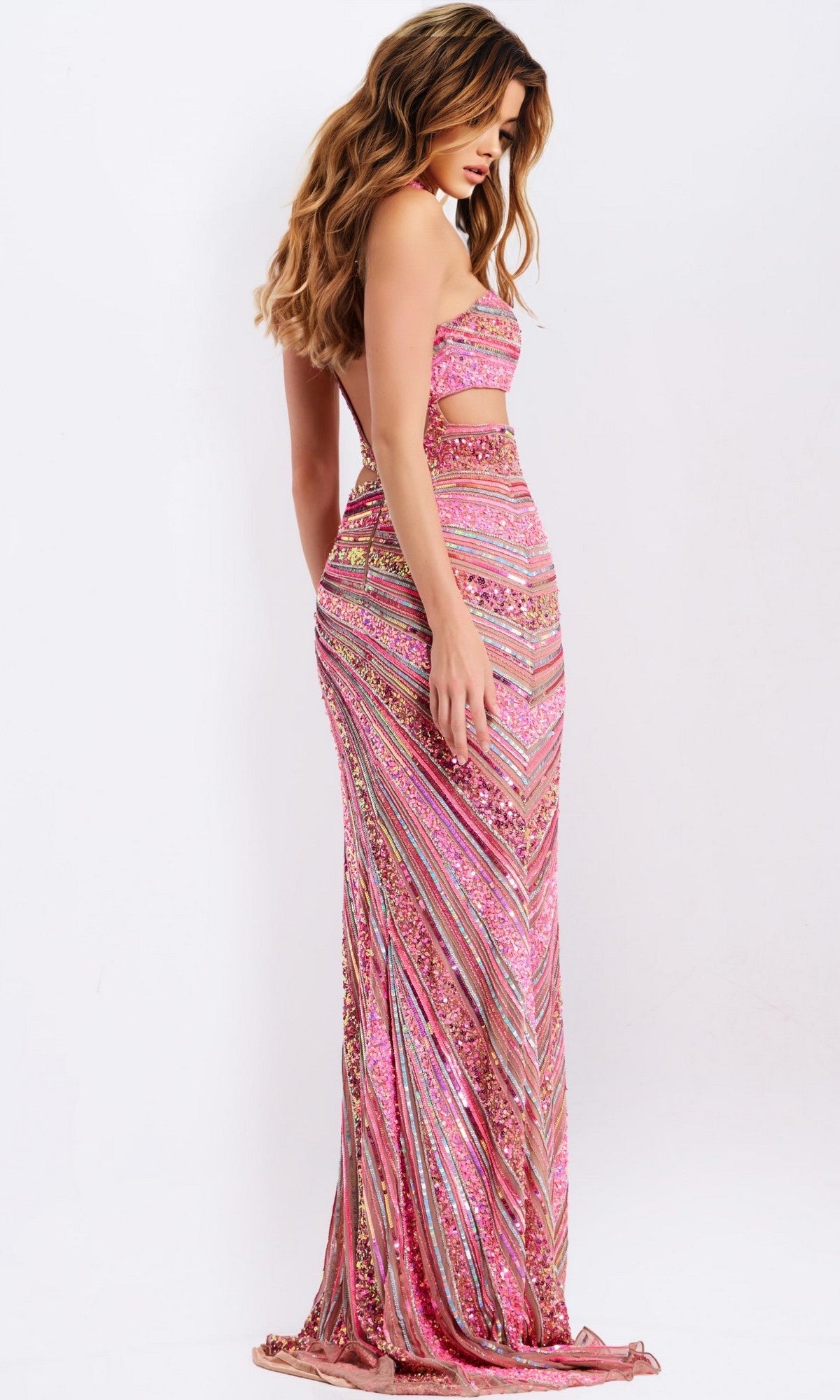 A woman stands sideways against a plain white background wearing the Jovani 49266, a long, strapless pink and gold prom dress with cutout details and a form-fitting silhouette.